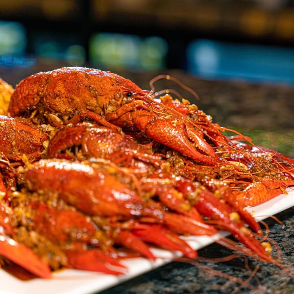Close-up of a large platter of Red Crab Juicy Seafood's seasoned, bright red crawfish.