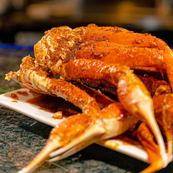 Close-up of Red Crab Juicy Seafood's snow crab legs, coated in a rich, spicy sauce.