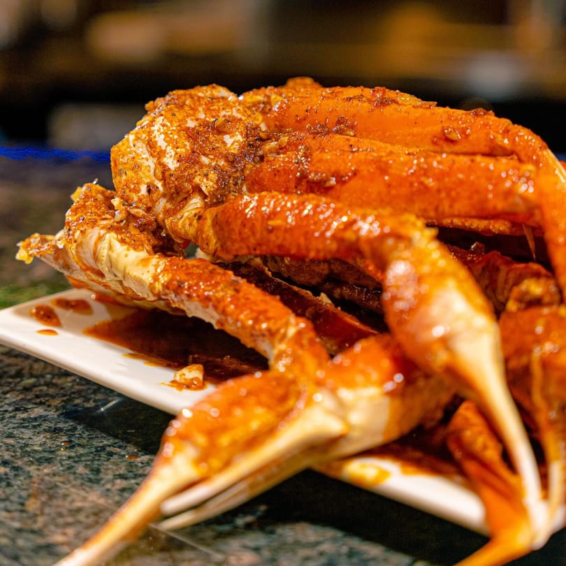 Close-up of Red Crab Juicy Seafood's snow crab legs, coated in a rich, spicy sauce.